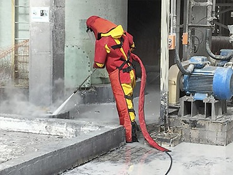 Técnico com traje de proteção realizando hidrojateamento de alta pressão